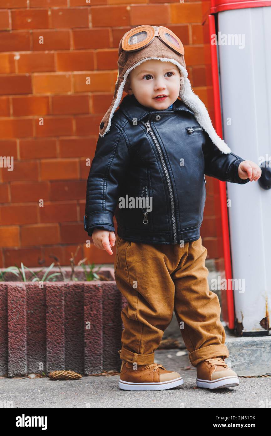 Niño con estilo de 3 años de edad con una chaqueta de cuero y pantalones  marrones camina por la calle. Niño moderno. Moda infantil. Niño feliz  Fotografía de stock - Alamy