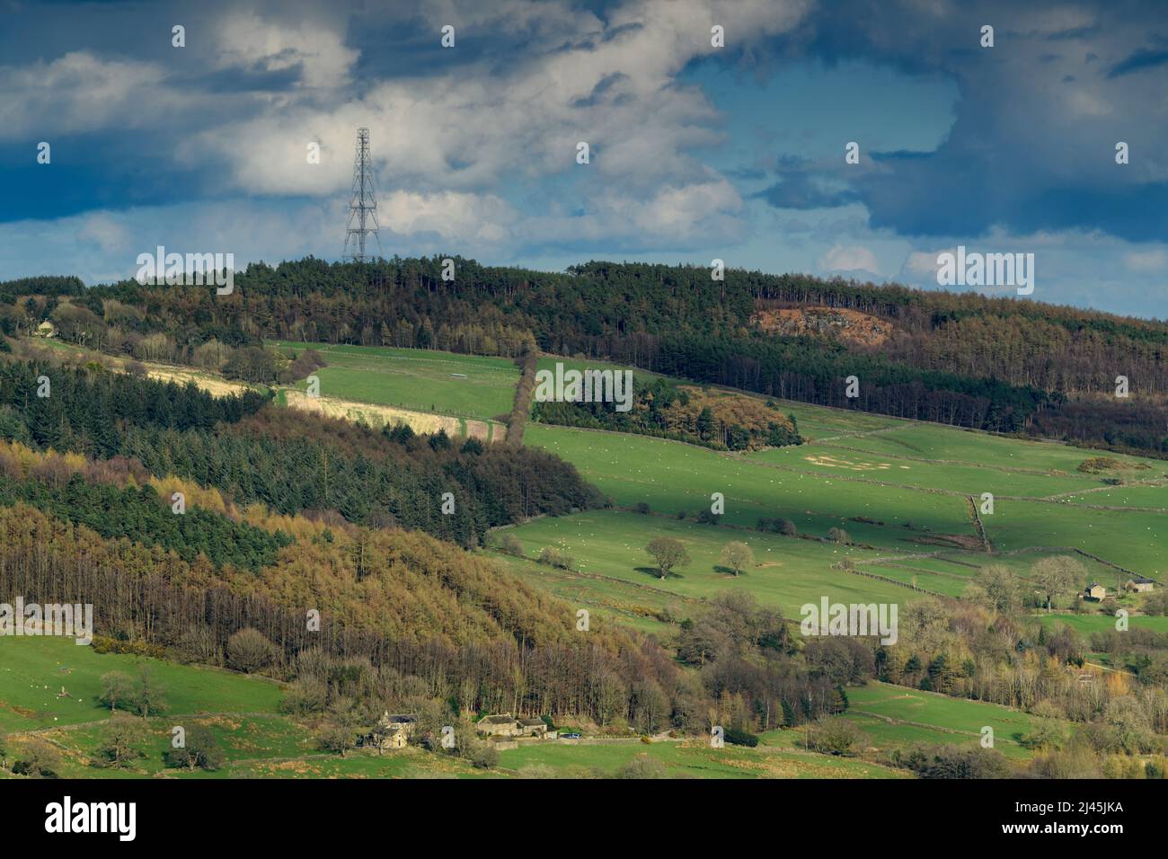 Paisaje rural soleado (laderas boscosas, pastos y pastos, mástil de retransmisión de tv y radio, cielo nublado) - Washburn Valley, Yorkshire, Inglaterra, Reino Unido. Foto de stock