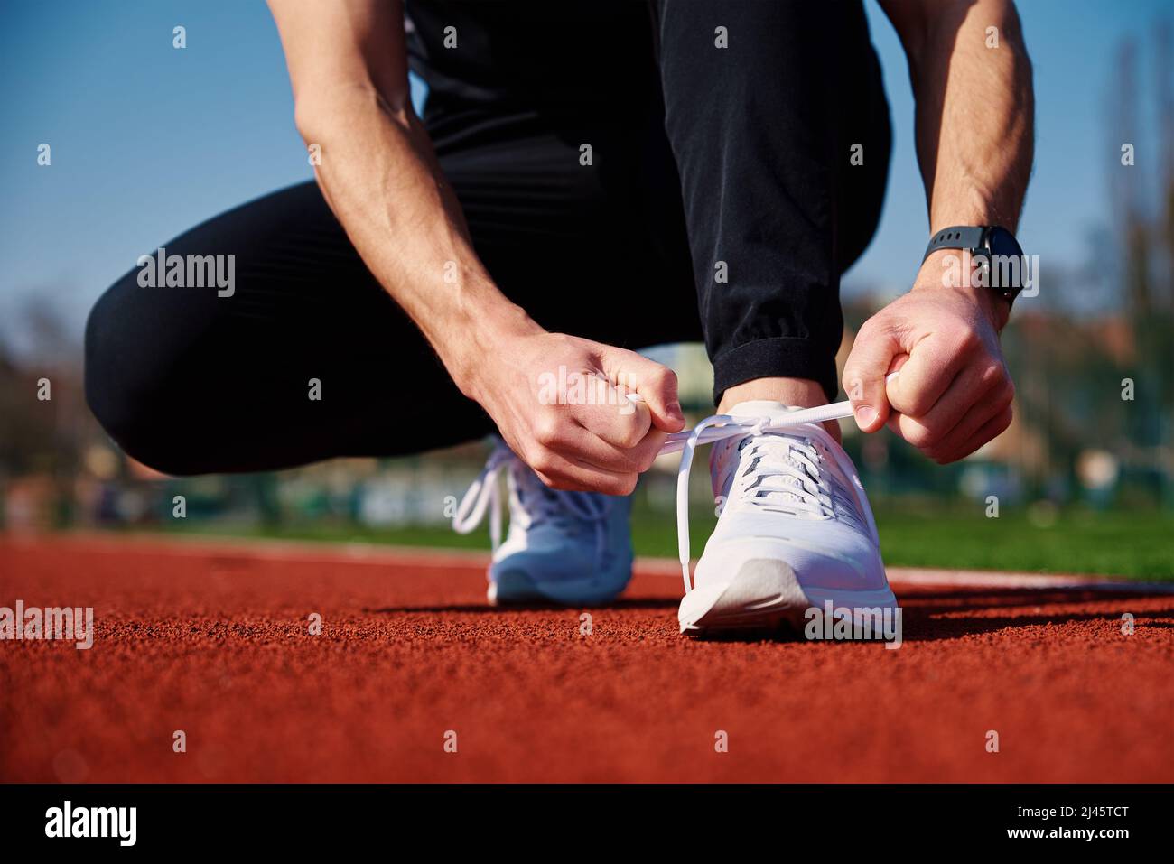 Las zapatillas de running para hombre en color blanco se preparan para correr en la pista del estadio. Manos masculinas atadas en zapatillas deportivas correr. Buen estado físico y estilo de