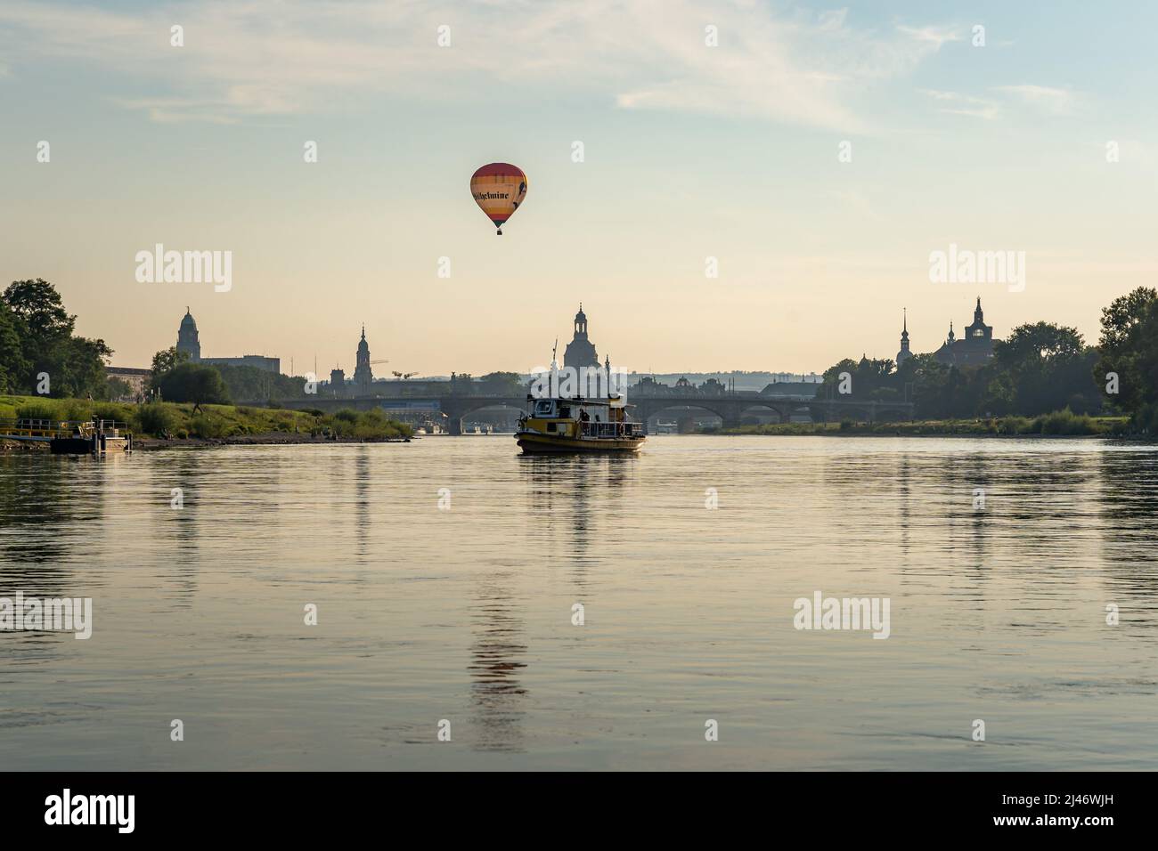 Un pequeño barco y un globo aerostático frente al famoso horizonte de la ciudad de Dresden. Diferentes modos de transporte en la ciudad. Edificios famosos. Foto de stock
