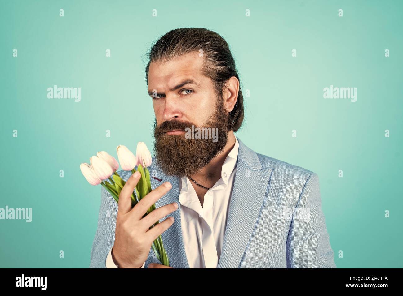 a él le gusta. hombre barbudo en ropa de vestir con flores de tulipán.  hombre de negocios elegante vestir elegante para el evento formal. regalo  de primavera. caballero verdadero Fotografía de stock -