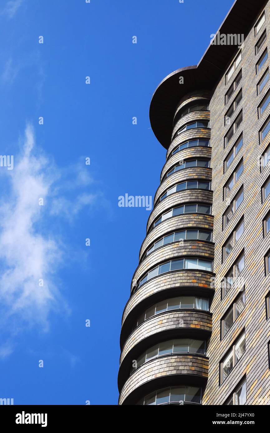 Vista exterior en ángulo bajo de un hermoso edificio moderno con apartamentos construidos como un rascacielos. Foto de stock