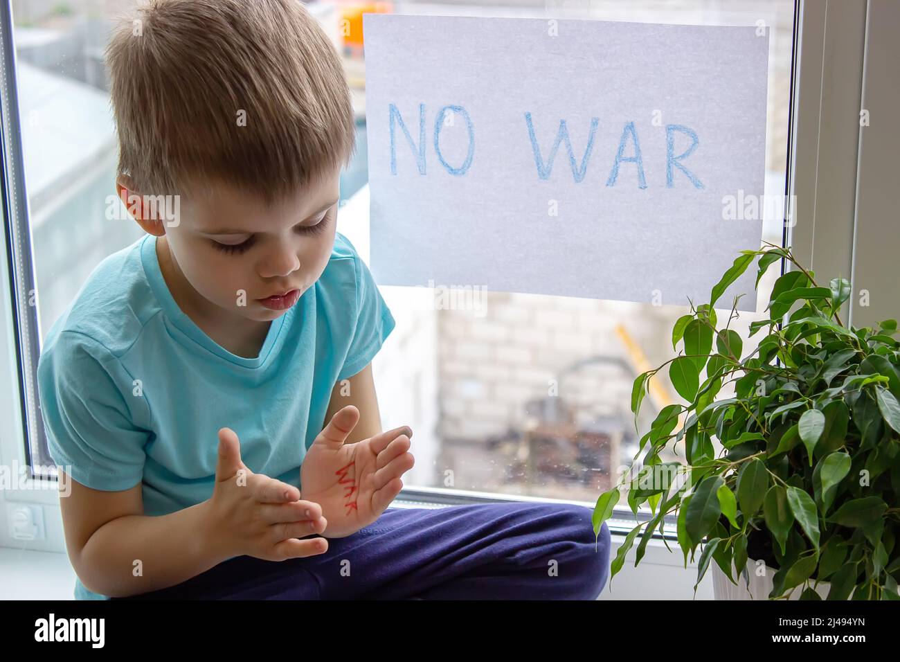 un niño está sosteniendo un pedazo de papel en el que se escribe no a la guerra. enfoque selectivo Foto de stock