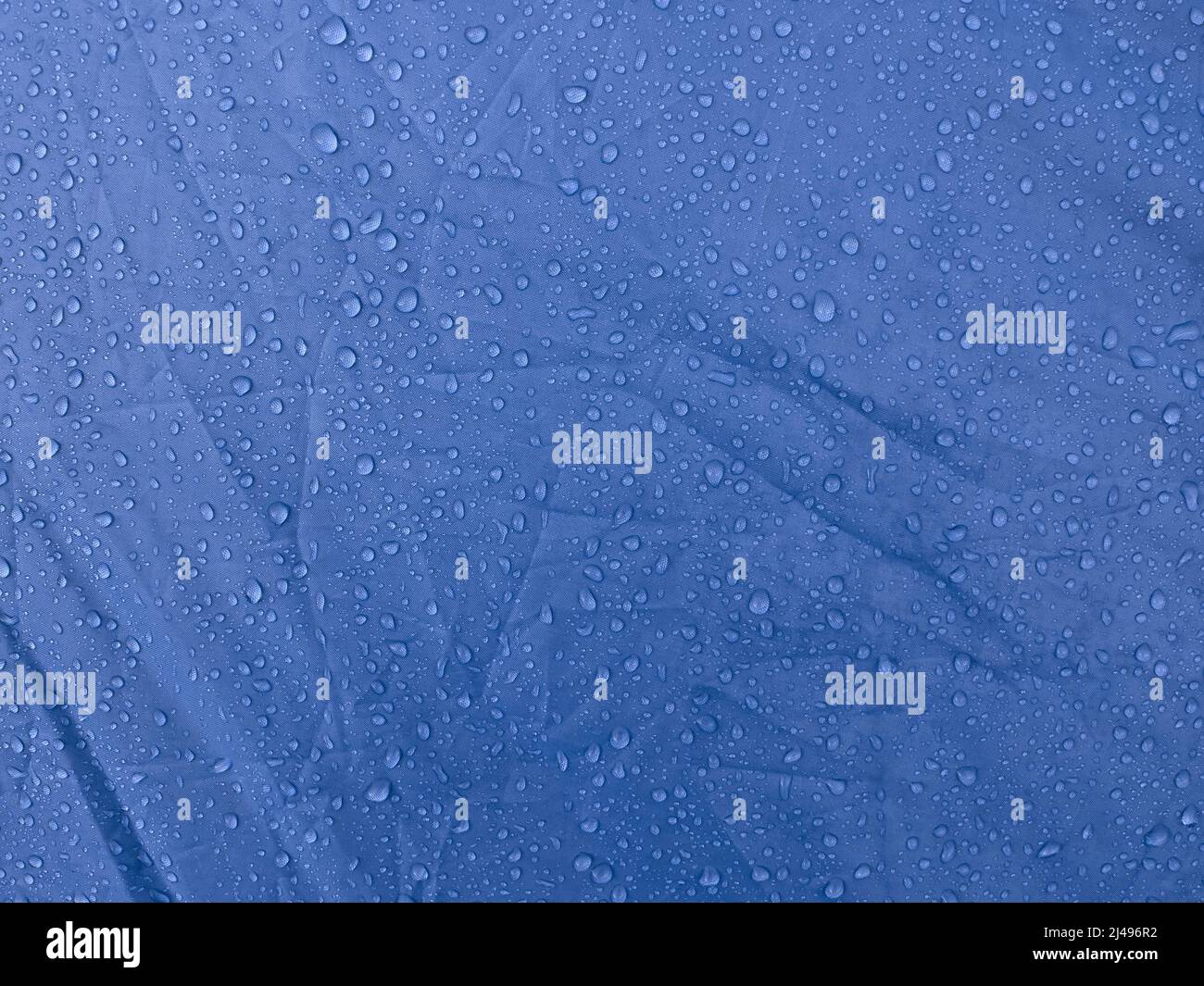 Gotas de agua sobre tejido de membrana impermeable. vista detallada de la  textura de la tela impermeable azul.