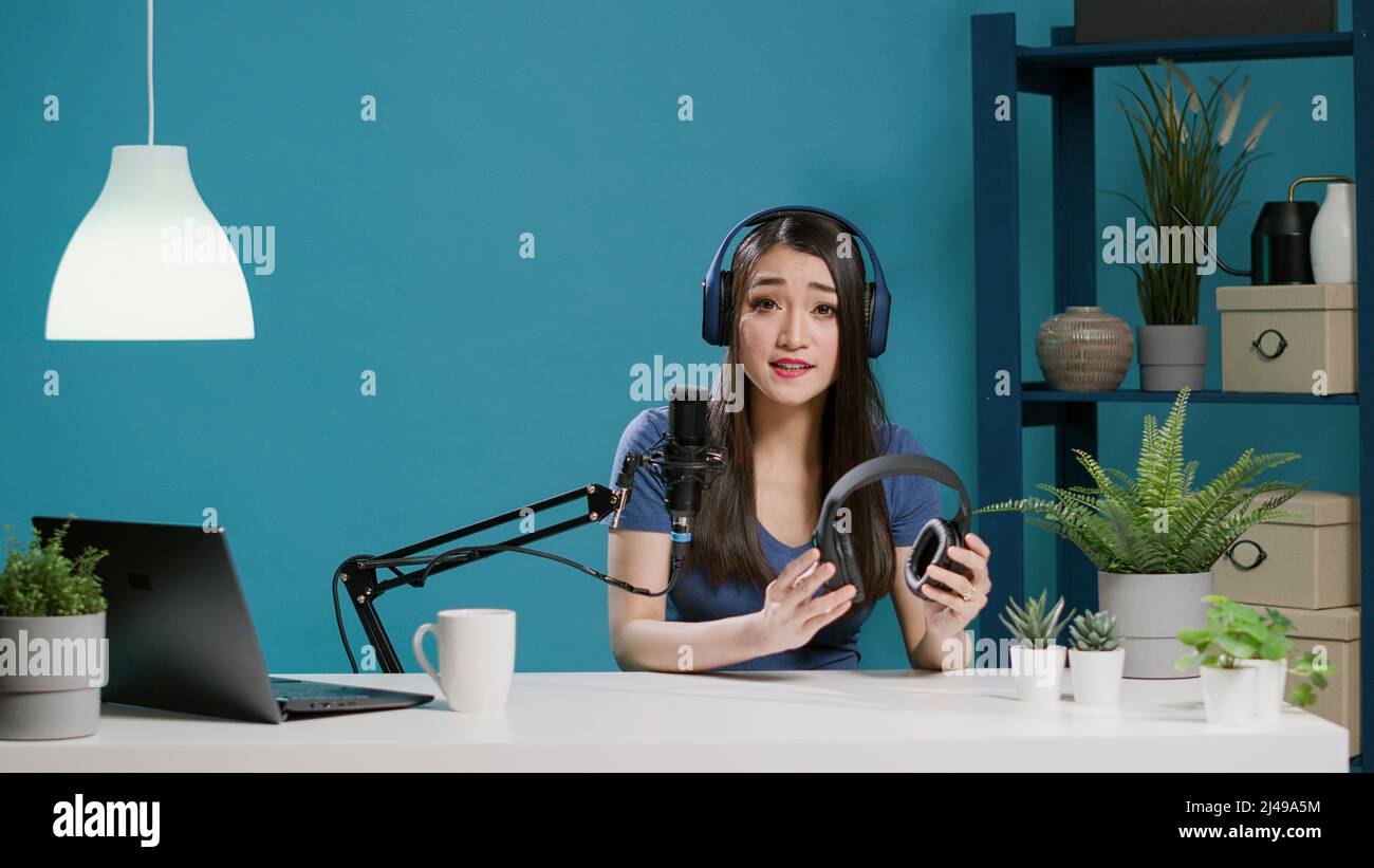 POV de mujer asiática que hace la recomendación de los auriculares modernos  en la cámara vlogging, filmando la revisión del producto con los auriculares  inalámbricos. Auriculares de sujeción para blogger Lifestyle. Disparo
