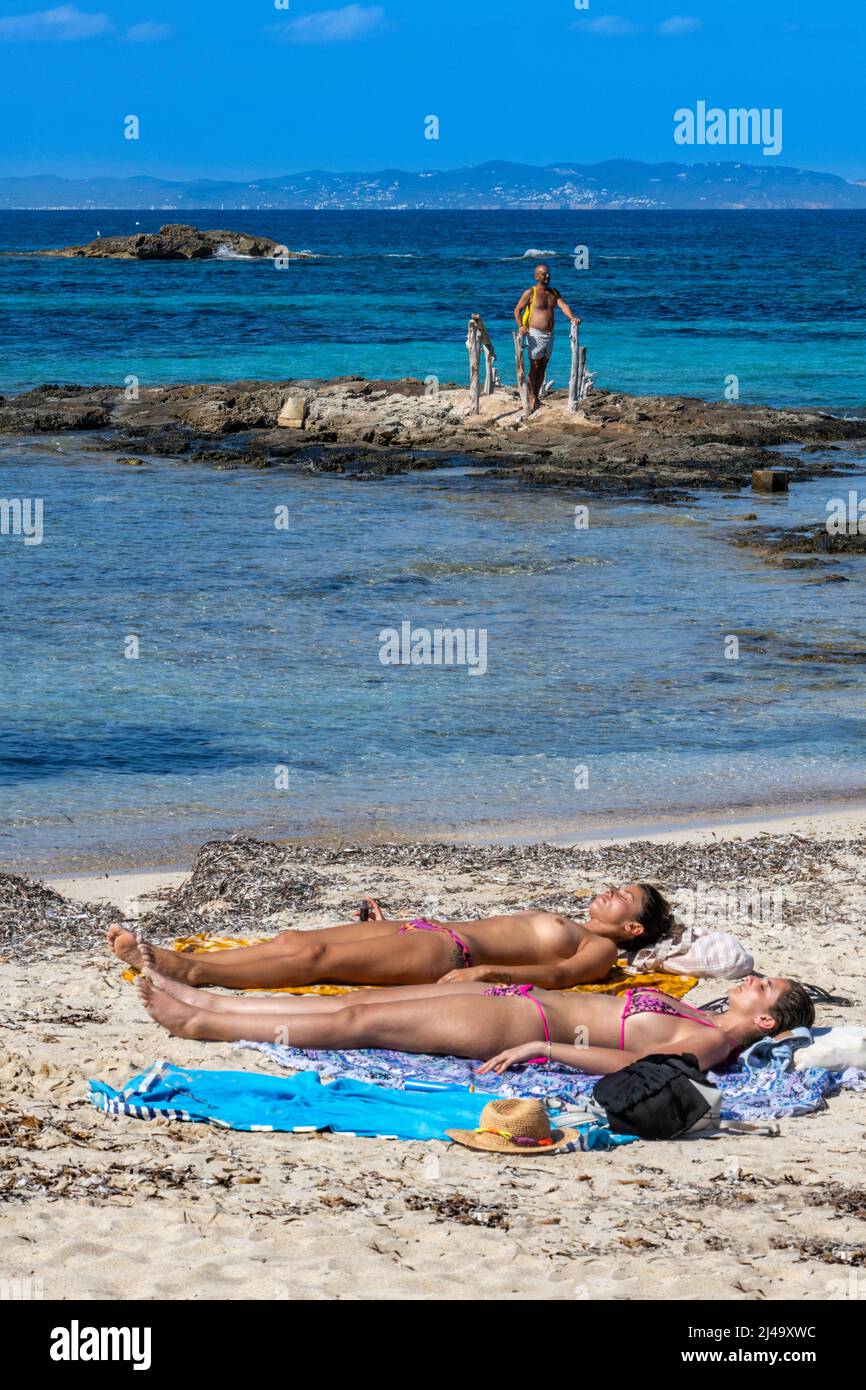 Dos chicas tomando el sol en la playa de Pujols, Islas Balearis, Formentera, España Foto de stock