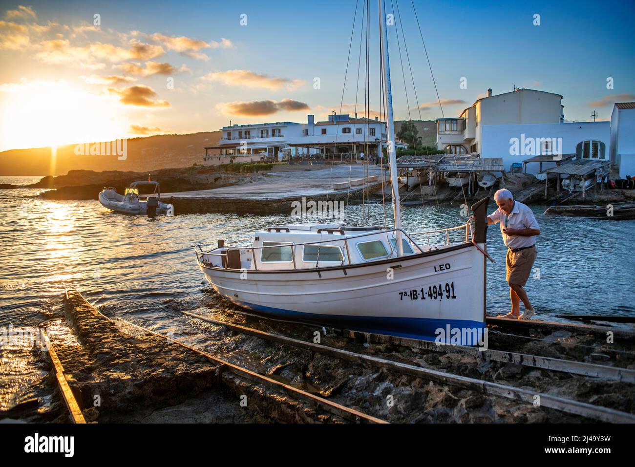 Pescador en un barco en el puerto del embarcadero de Es Caló de San Agustí en Formentera isla barcos de madera en Formentera Islas Baleares España Foto de stock