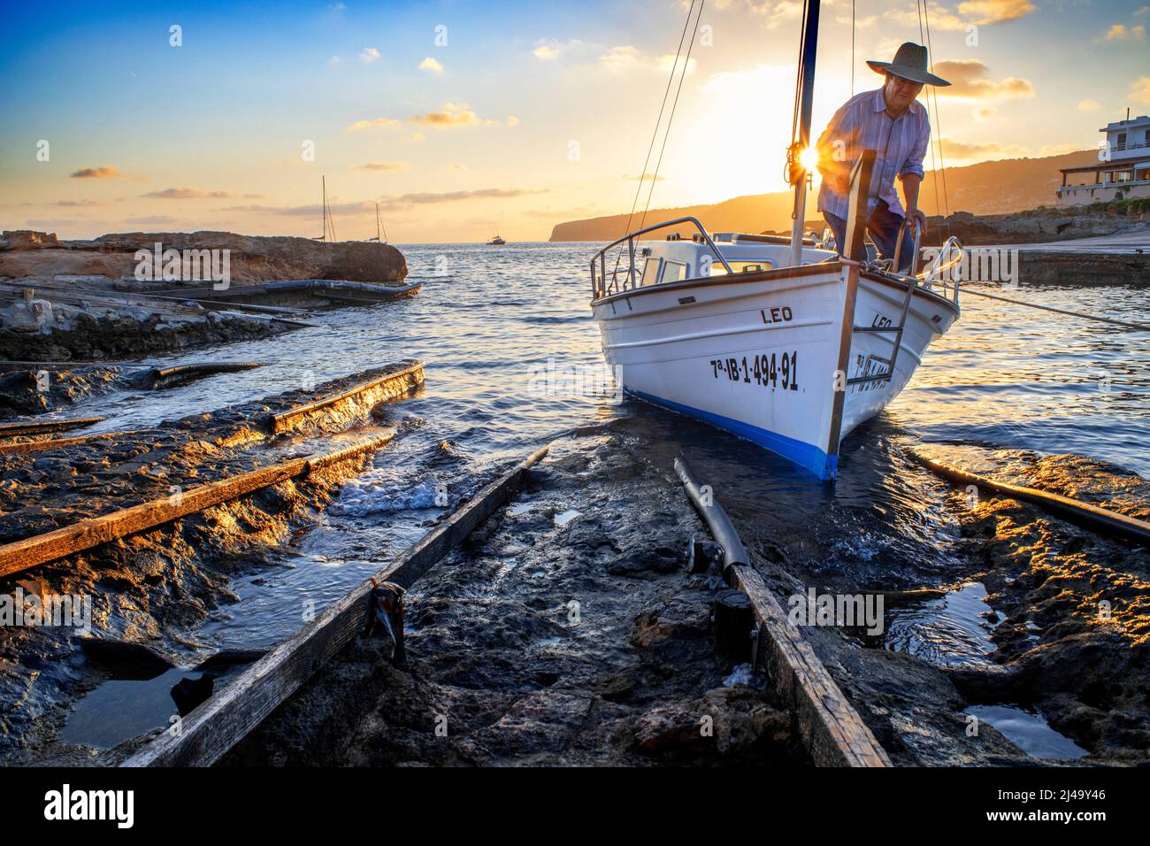Pescador en un barco en el puerto del embarcadero de Es Caló de San Agustí en Formentera isla barcos de madera en Formentera Islas Baleares España Foto de stock