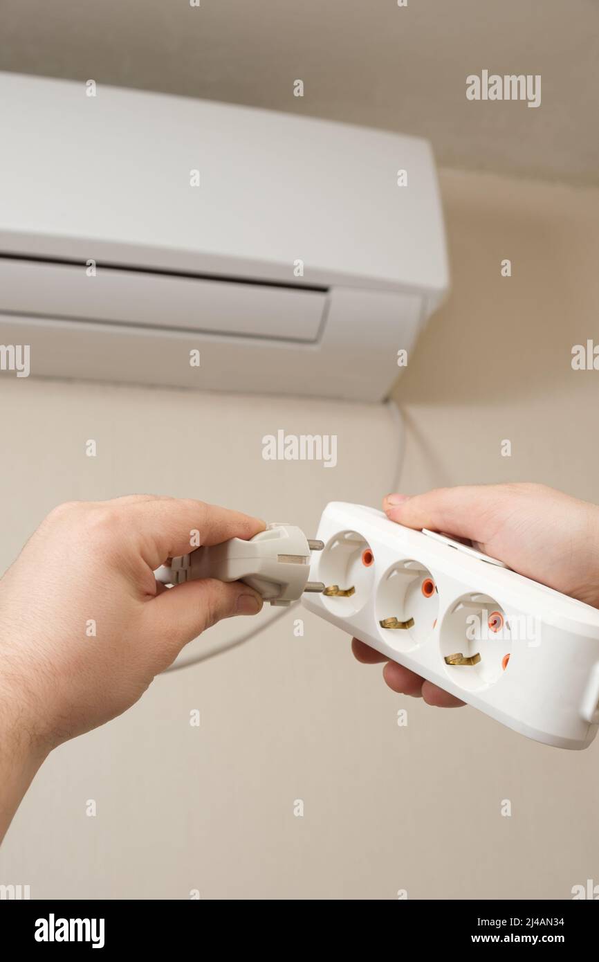 La persona conecta el enchufe del acondicionador de aire en la salida  Fotografía de stock - Alamy