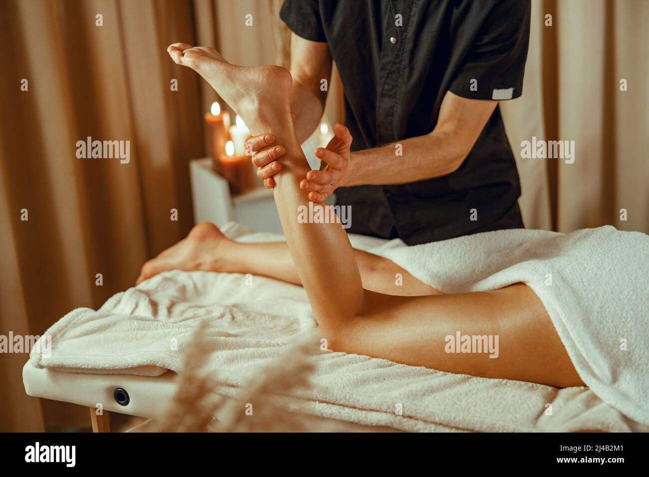 Masajista profesional masculino haciendo masaje de pies mujer en el salón del spa Foto de stock