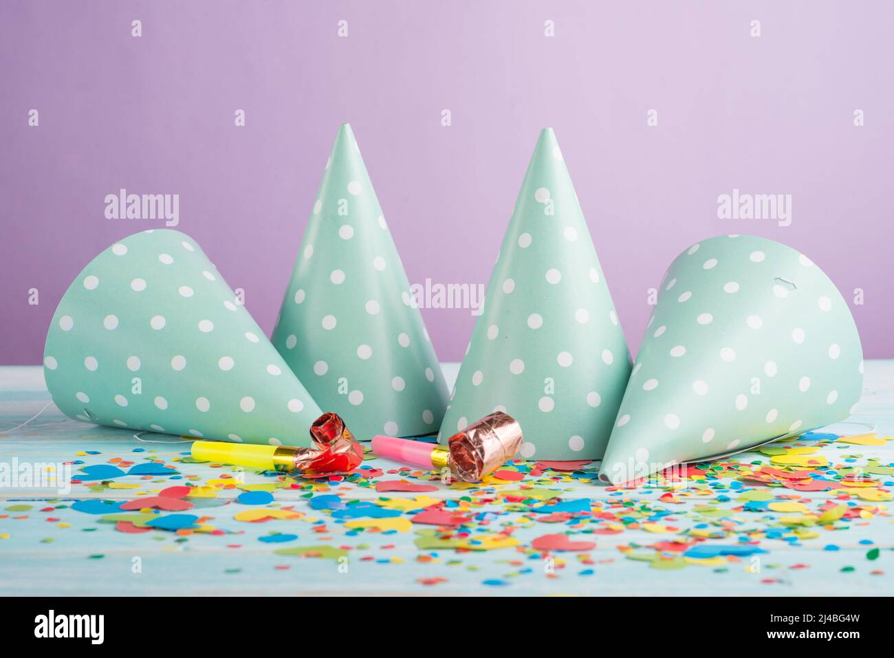 Gorras de cumpleaños, soplantes y confeti en el fondo Foto de stock