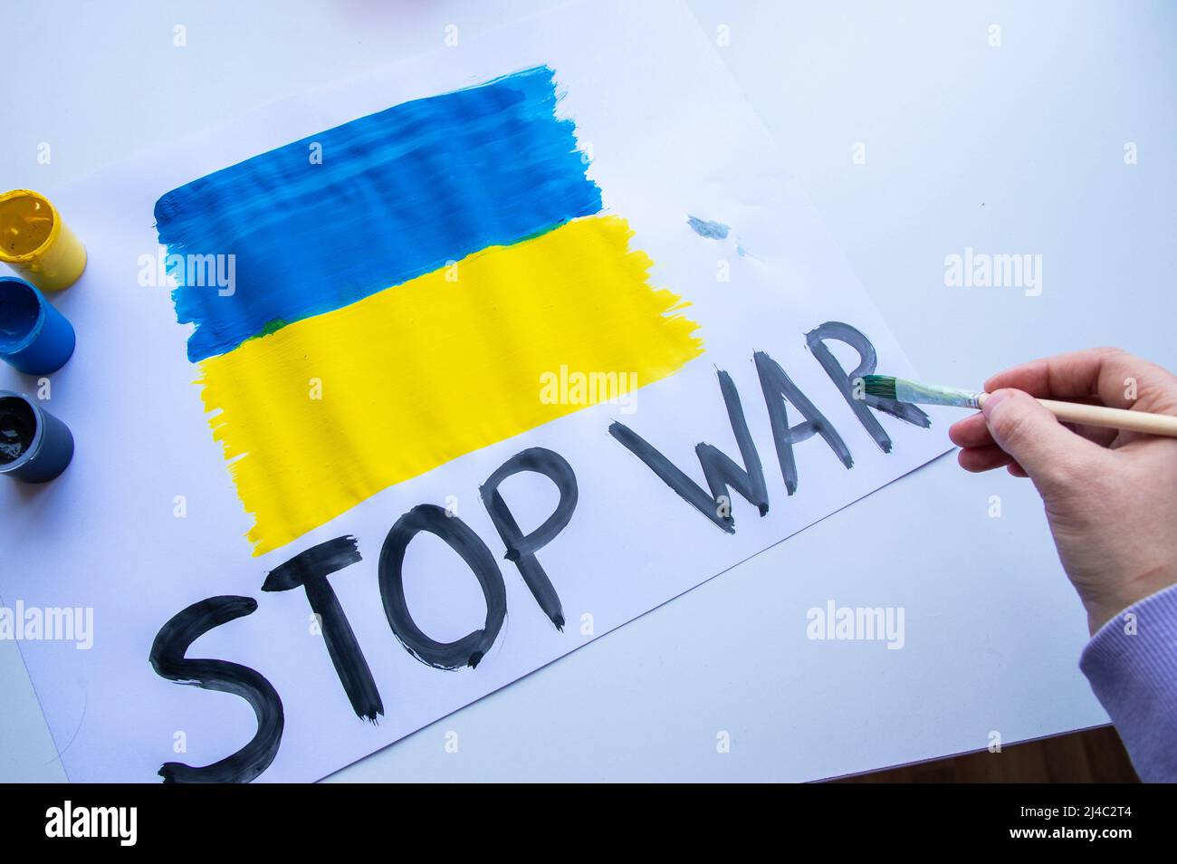 Una mujer pinta un cartel con la bandera de Ucrania Foto de stock