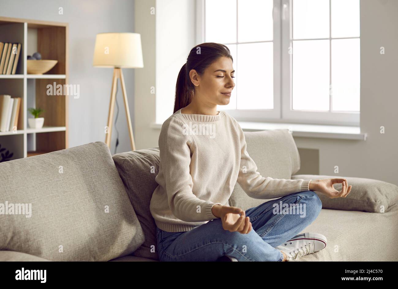 Mujer joven practica yoga medita en casa Foto de stock