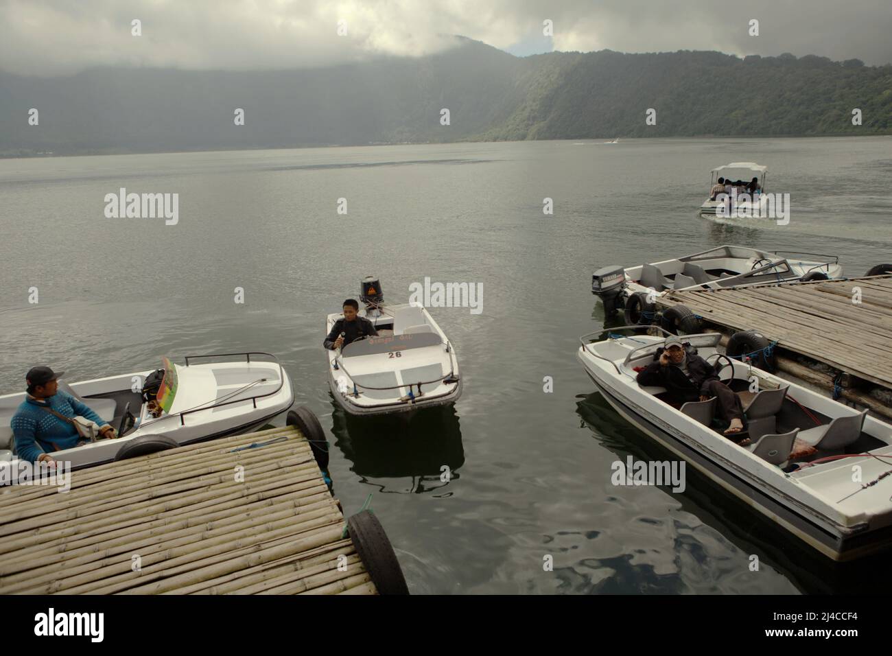 Los turistas domésticos se preparan en barcos en el embarcadero de la zona recreativa de deportes acuáticos de Bedugul en el lago Bratan, Bedugul, Tabanan, Bali, Indonesia. Foto de stock