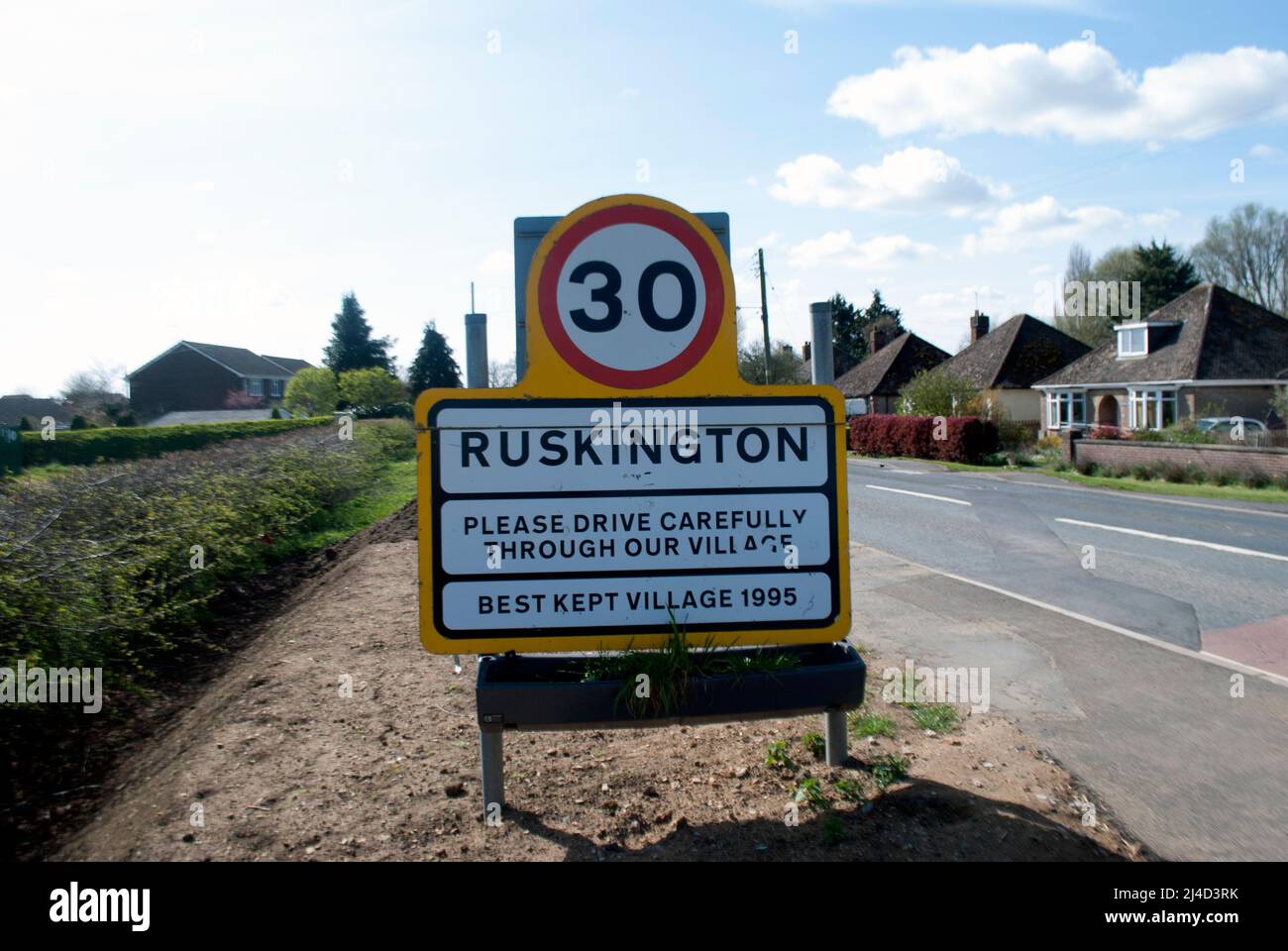 Cartel del nombre del pueblo para Ruskington y límite de velocidad de 30 mph al lado de la carretera que conduce a Ruskington, Sleaford, Lincolnshire, Inglaterra, Reino Unido Foto de stock