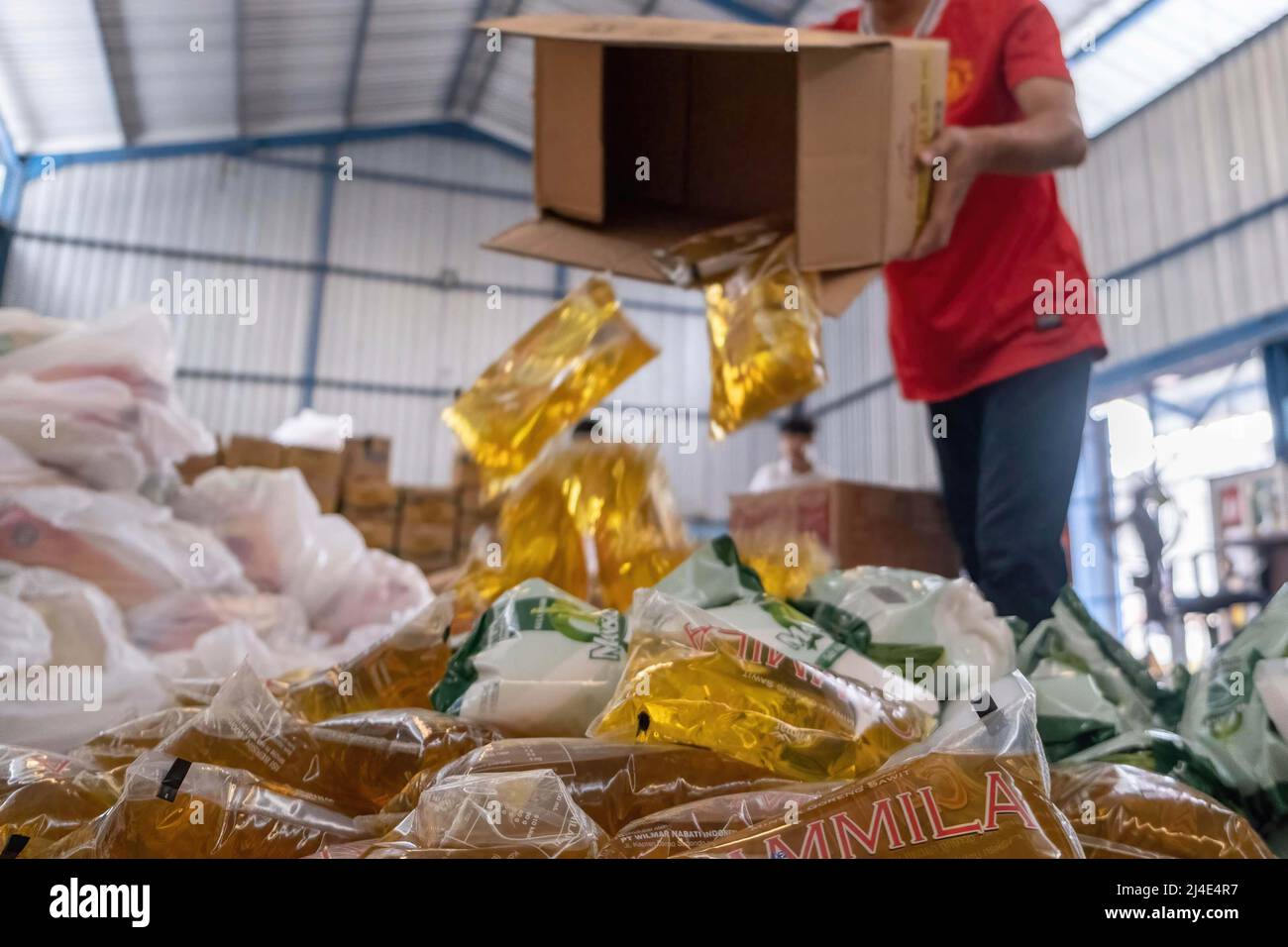 Un trabajador desempaqueta una caja de paquetes de aceite de cocina para  agregarlos a paquetes de alimentos para venderlos a la gente. Después de  mediados de marzo los precios se dispararon debido