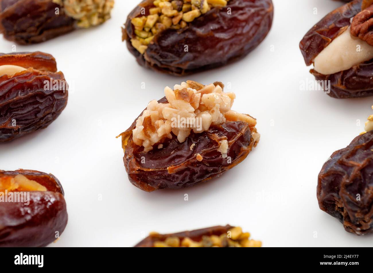 Dulces de Ramadán y una lujosa selección del concepto de dátiles dulces de jumbo con primeros planos en la fecha de medjool rellena de pistacho y relleno de nogal aislado en w Foto de stock