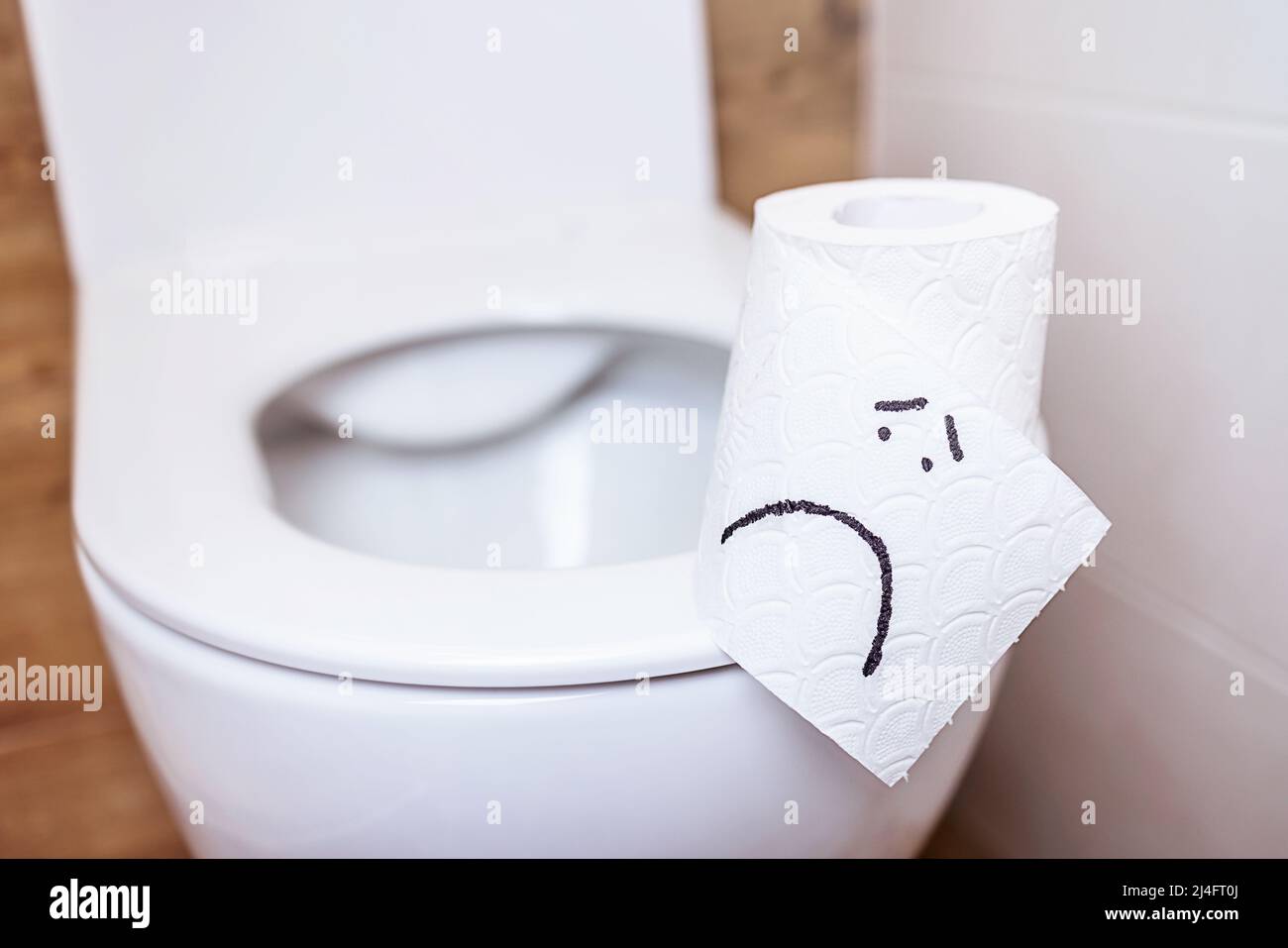 rollo de papel higiénico con una cara triste cuelga se coloca en el inodoro  con una tapa abierta Fotografía de stock - Alamy