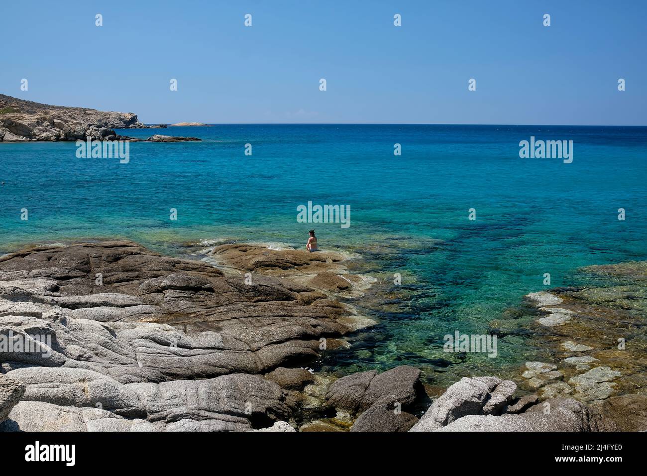 IOS, Grecia - 12 de junio de 2021 : Una mujer soltera tomando el sol en la increíble playa rocosa de Pikri Nero en Ios Grecia Foto de stock