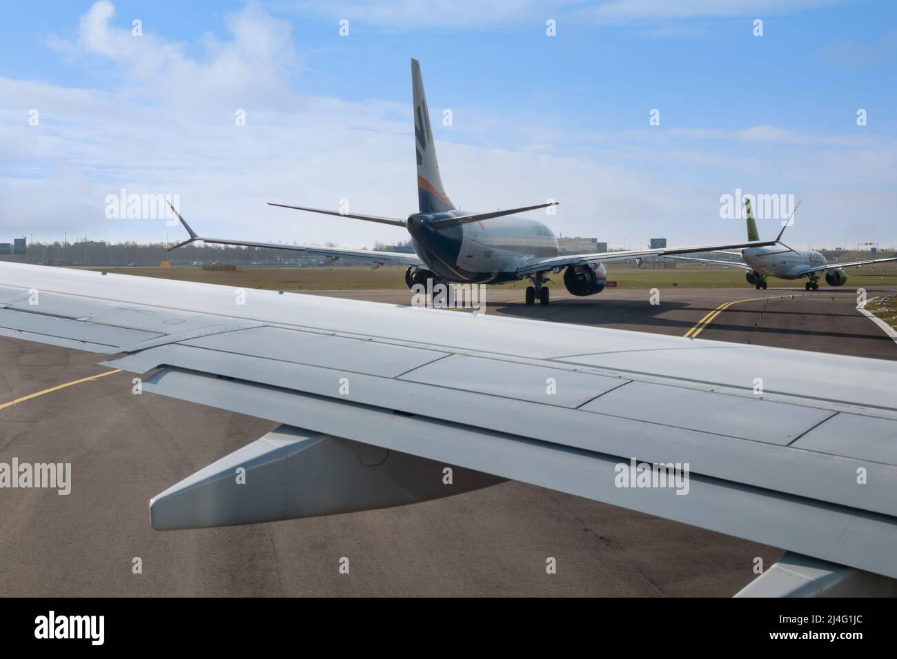 Schiphol, Países Bajos - 02 de marzo de 2022: Tres aviones en cola en la pista, listos para despegar en el aeropuerto de Schiphol Foto de stock