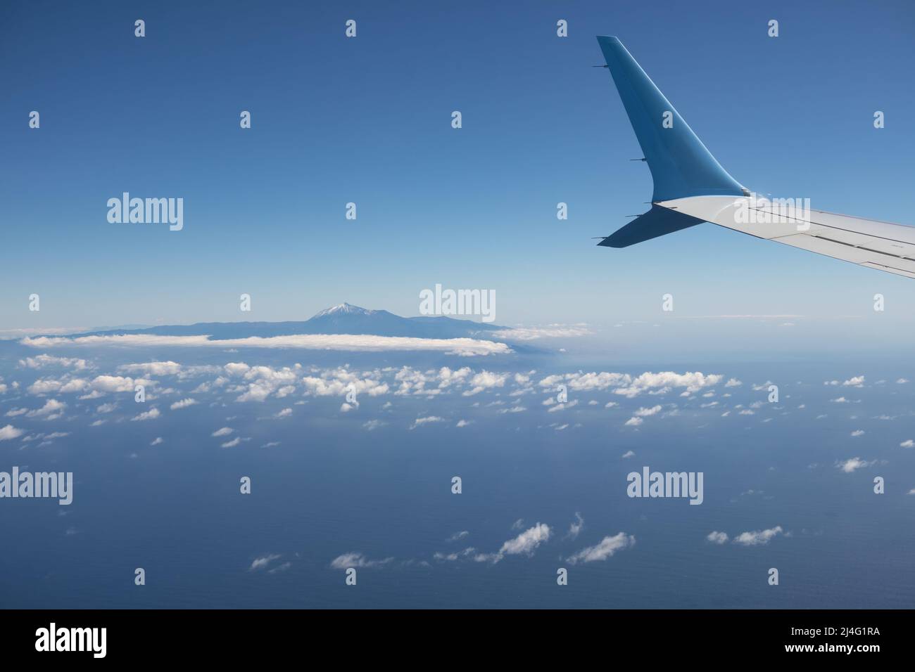 Ala de un avión volando sobre el Océano Atlántico con vista a la isla Tenerife con el monte Teide Foto de stock