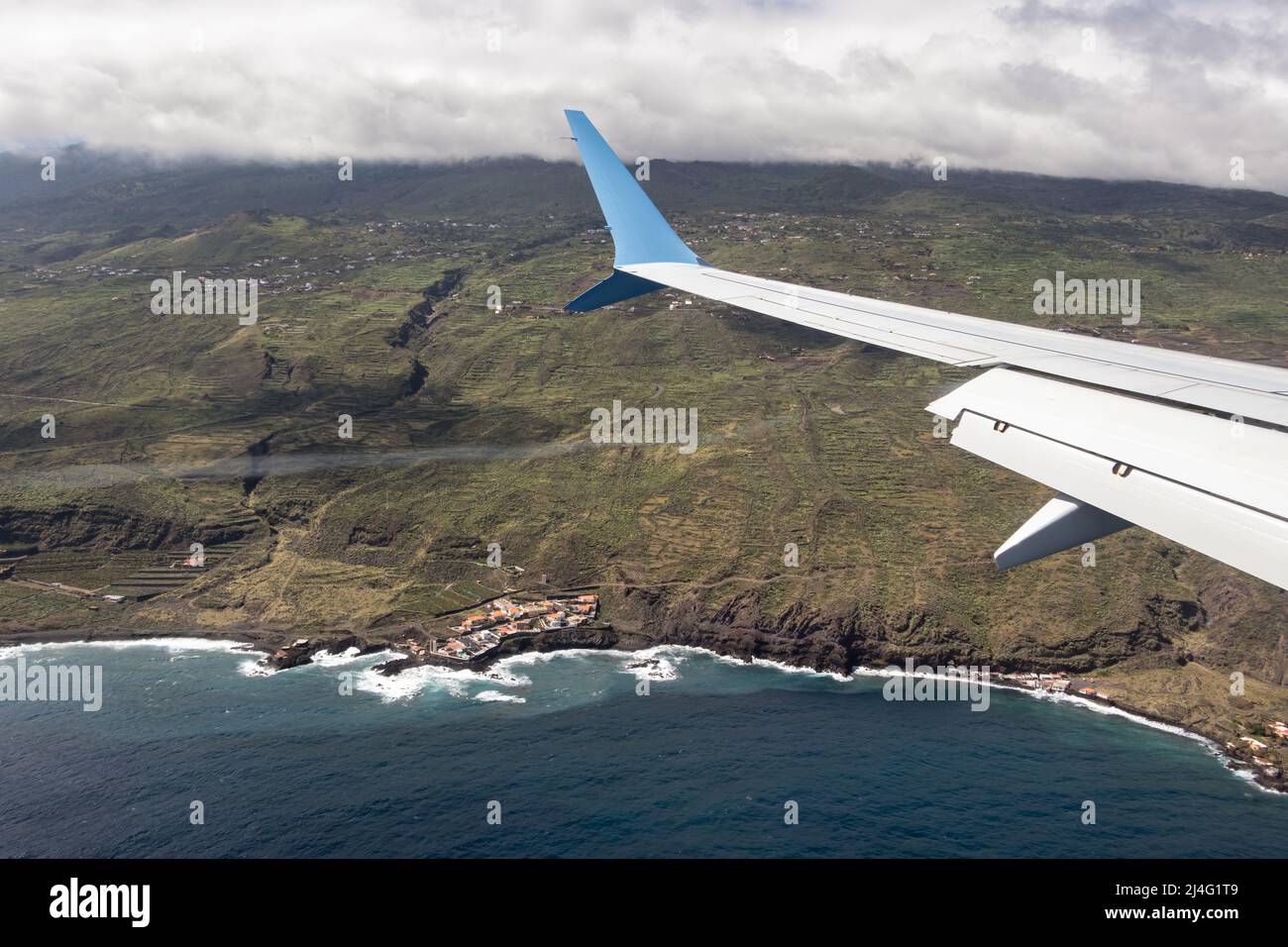 Ala de un avión que vuela sobre el Océano Atlántico acercándose a la Isla Canaria La Palma Foto de stock