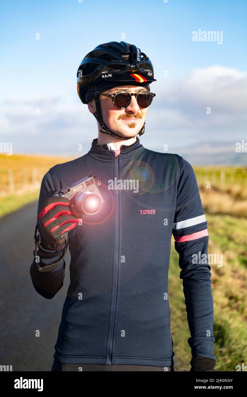 Fotógrafo ciclista masculino posando con su cámara de cine Leica M6 en Yorkshire Dales, Reino Unido. Foto de stock