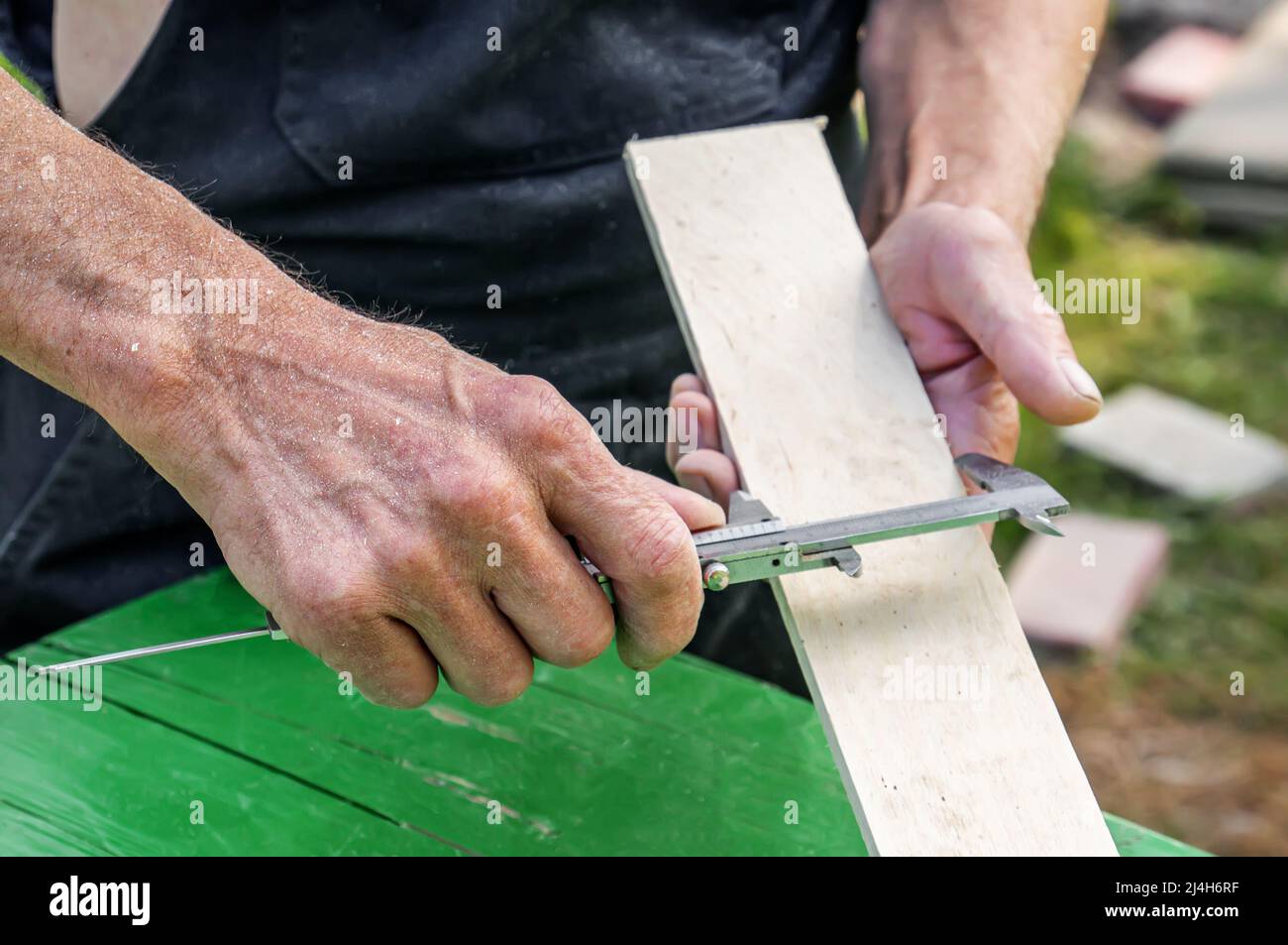 turner mide el tablero con una herramienta. mesa de sierra. Un carpintero  experimentado está listo para cortar una tabla de madera con una sierra  circular. Producción de mate de madera Fotografía de