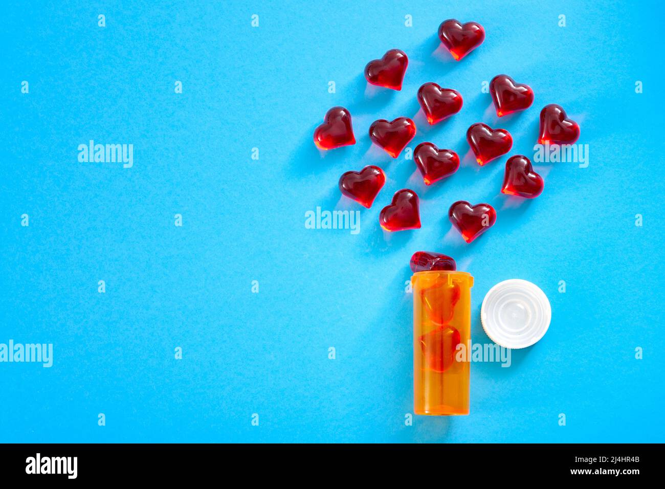 Día de San Valentín, el amor es una droga y la cura para el concepto de dolor de corazón con muchos corazones dispersos de una botella de píldoras de prescripción aislada en minimali Foto de stock