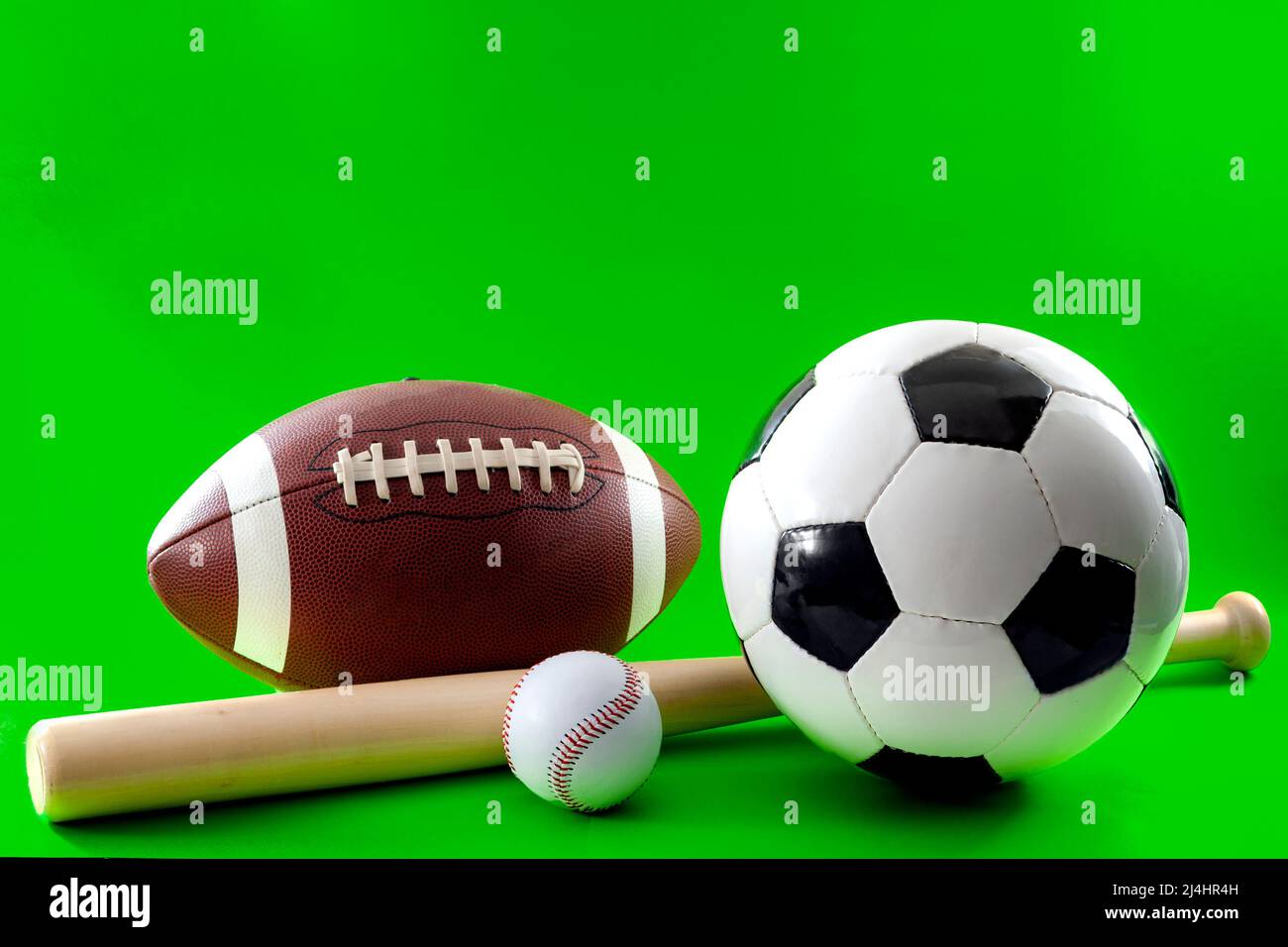 Equipo deportivo y concepto de actividades de ocio con un bate de béisbol y múltiples pelotas utilizadas en diferentes deportes, como el fútbol americano, el béisbol y así Foto de stock