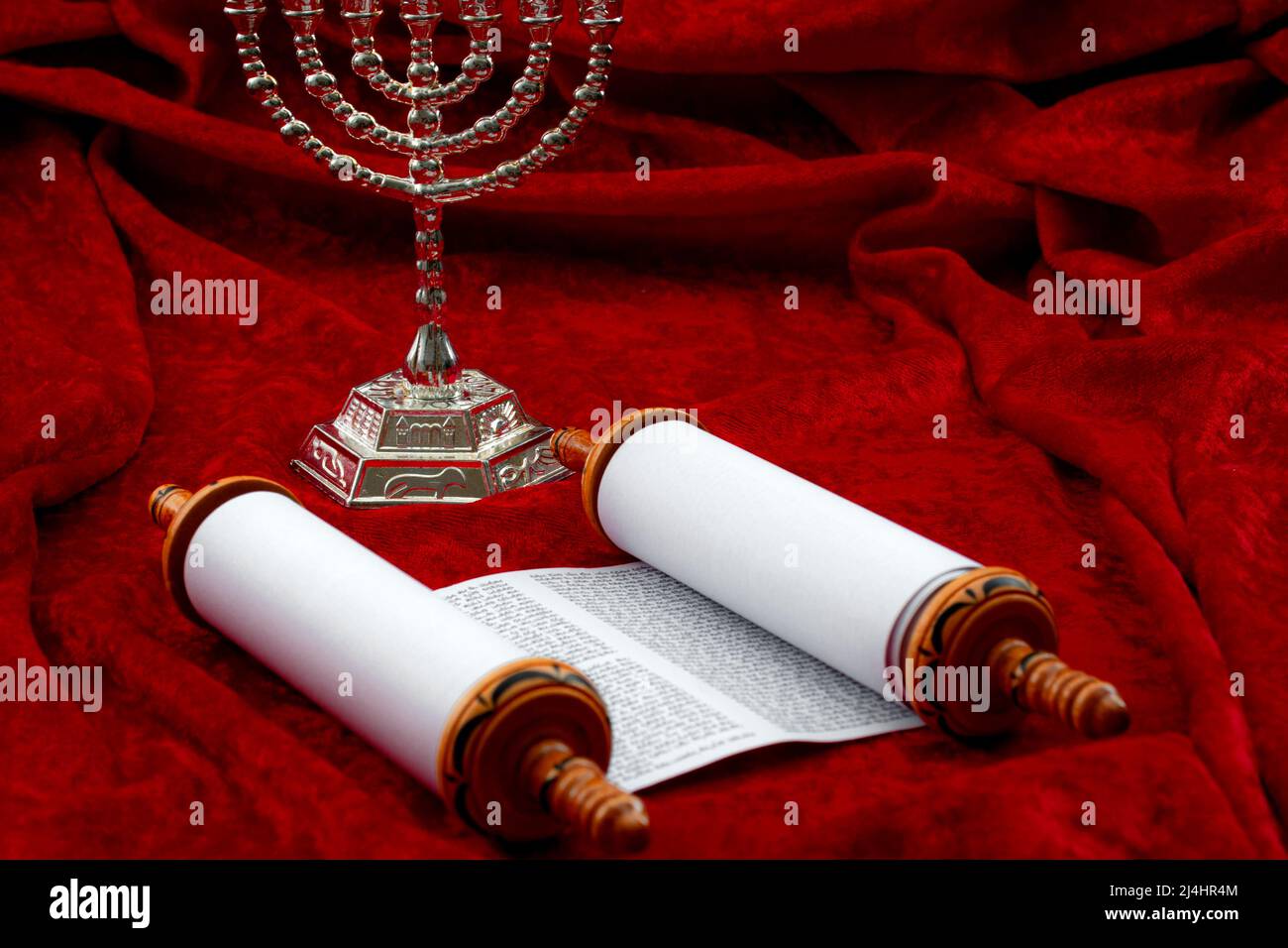 Feliz Hanukkah, espiritualidad religiosa y tema de concepto de oración con menorah y rollos de Torah aislados sobre fondo de terciopelo rojo con espacio de copia en J Foto de stock