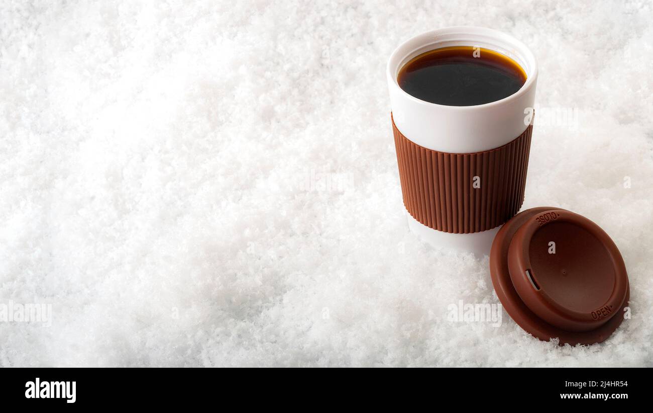 Café caliente en una taza de papel con nieve aislada sobre fondo blanco con espacio para copias Foto de stock