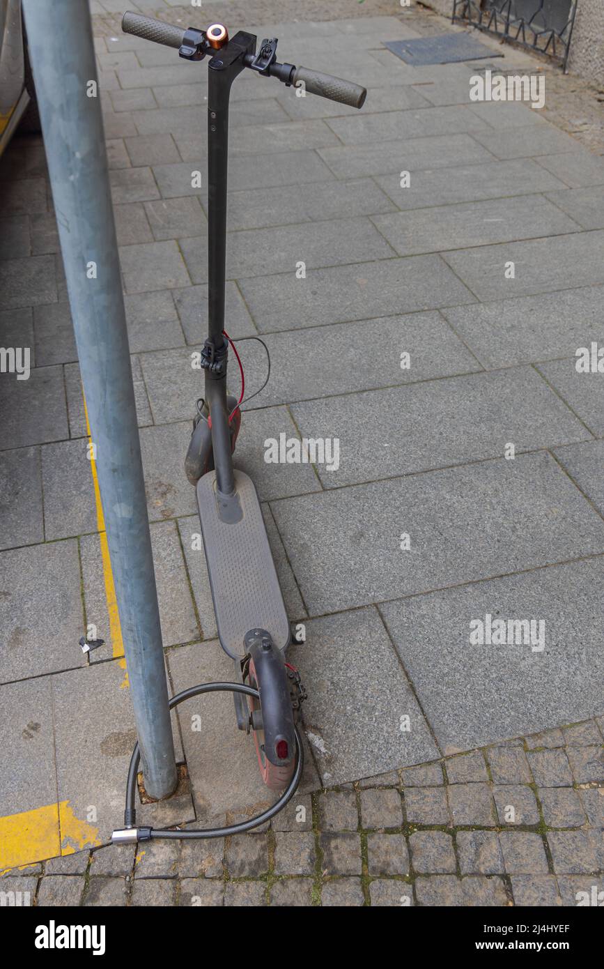 Rueda trasera de la scooter eléctrica antirrobo bloqueada en el poste  Fotografía de stock - Alamy