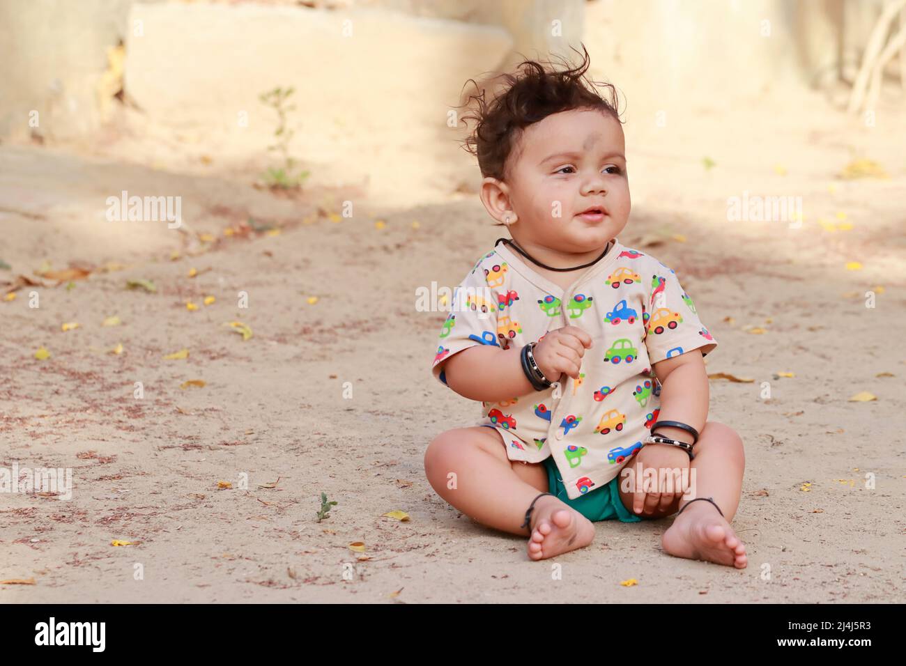 Primer plano de la foto retrato de Un bebé hindú pequeño recién nacido lindo sentado en el suelo con una cara sonriente, india Foto de stock