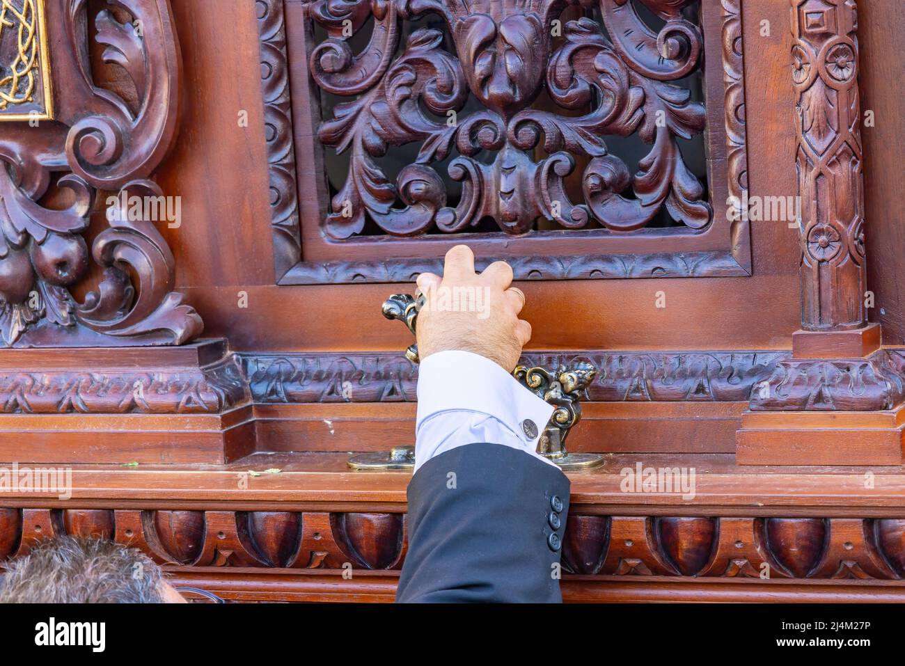 Detalle de la mano del capataz en el knocker justo en el momento en que