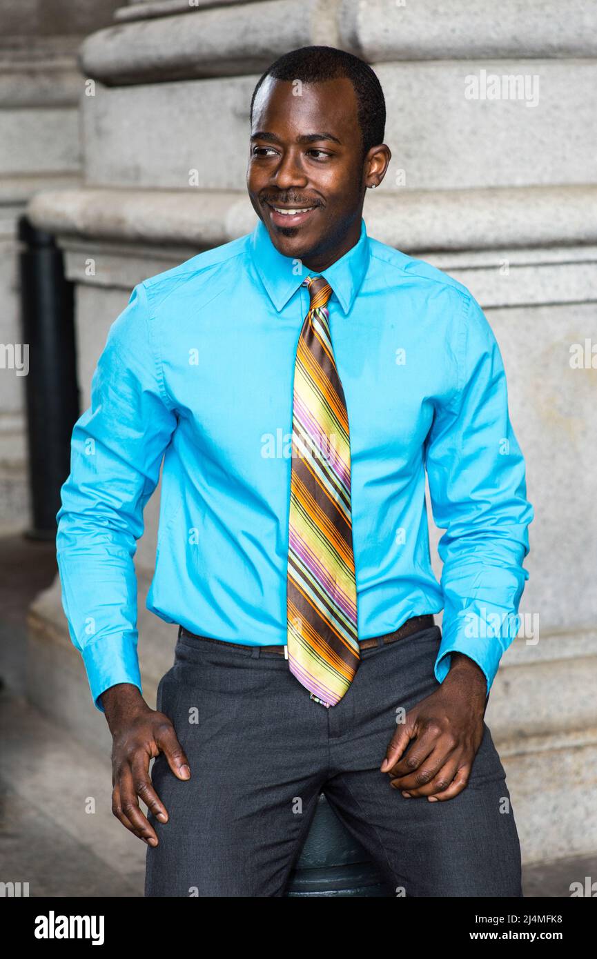 Puntero pesadilla Expectativa Vestida con una camisa azul claro, una corbata de colores, un joven hombre  de negocios negro está sonriendo, sentado afuera para tomar un descanso  Fotografía de stock - Alamy