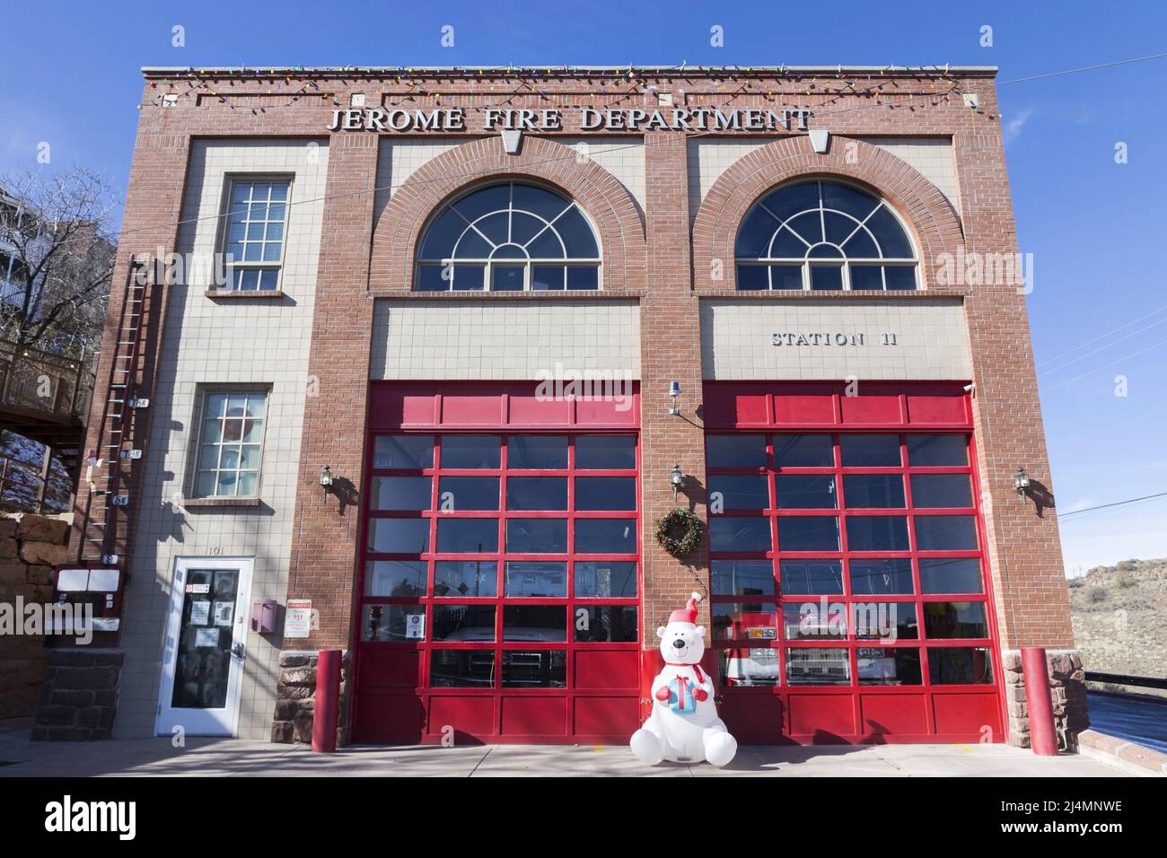 Vista frontal del edificio de la estación de bomberos en Jerome, Arizona Main Street con figura de Santa Claus en frente de las puertas del garaje Foto de stock