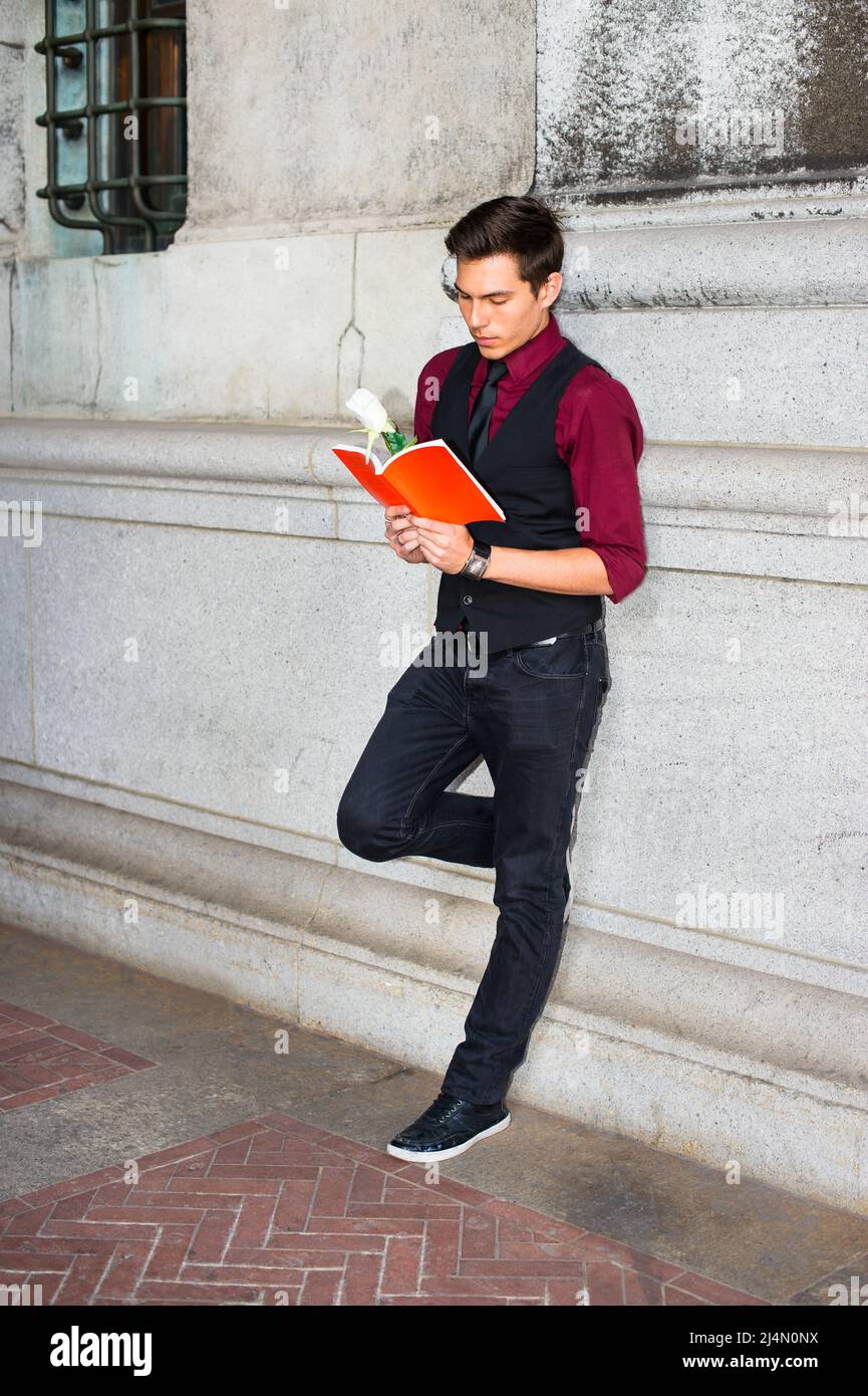 Vestirse en una camisa roja, un chaleco negro, jeans negros y una corbata  negra, un joven guapo está leyendo un libro rojo con una rosa blanca  Fotografía de stock - Alamy