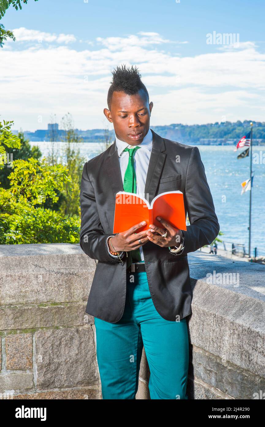Hombre leyendo afuera. Vestirse en una camiseta blanca, un blazer pantalones verdes, una corbata verde, un libro rojo, un joven negro con pelo mohawk Fotografía de stock - Alamy