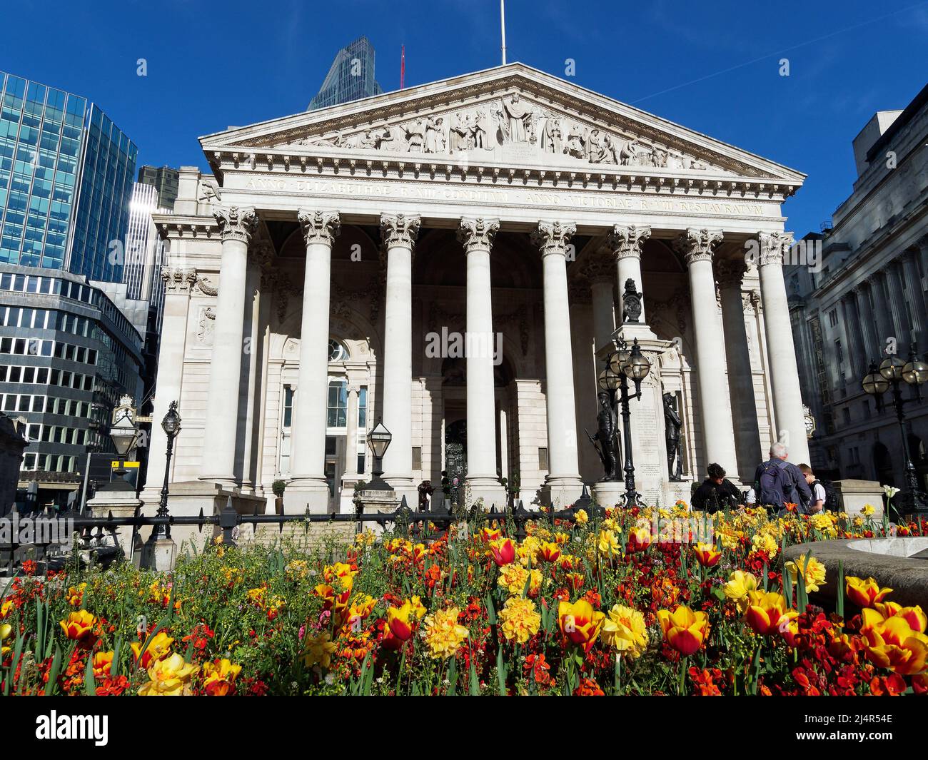Vista frontal de la Royal Exchange en Londres en un día de primavera brillante con coloridas flores de primavera en primer plano Foto de stock