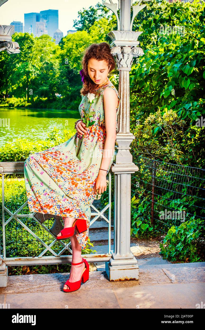 Señora que te falta en el parque. Bonita adolescente vestido sin mangas,  verde claro, vestido largo, zapatos de sandalias rojas, sentado dentro del  pabellón, mano de sujeción wh Fotografía de stock -