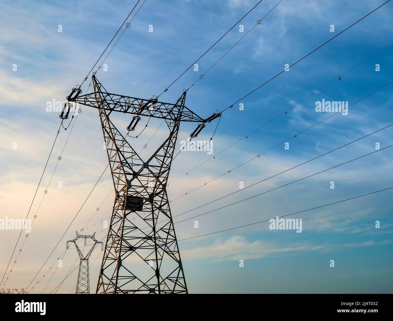 Grandes torres de distribución de electricidad al atardecer Foto de stock