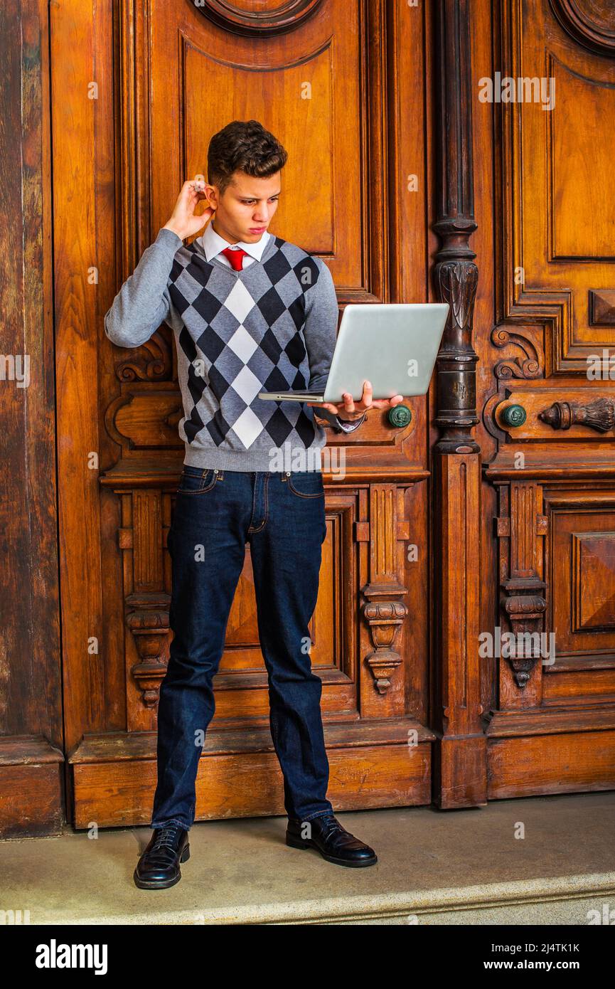 Estudiante de American College que estudia en Nueva York. Usando un suéter  estampado, corbata roja, jeans azules, zapatos de cuero, un chico joven  está parado fuera de fuera de Ofic Fotografía de