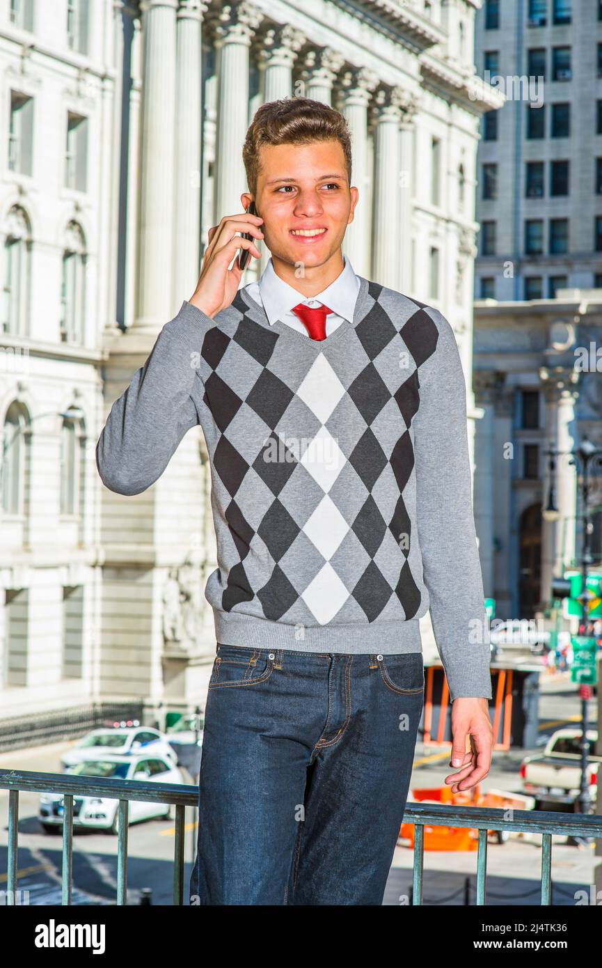 Hombre llamando fuera. Vestirse en un suéter estampado negro, blanco, gris,  jeans, un joven hombre de negocios guapo está de pie en la parte delantera  de un bui de oficina Fotografía de