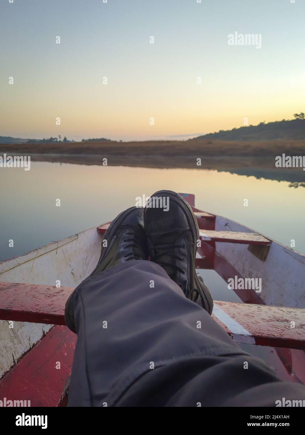 el hombre se embarcan en un tradicional barco de madera en un lago tranquilo con un espectacular amanecer y colorido reflejo del cielo Foto de stock