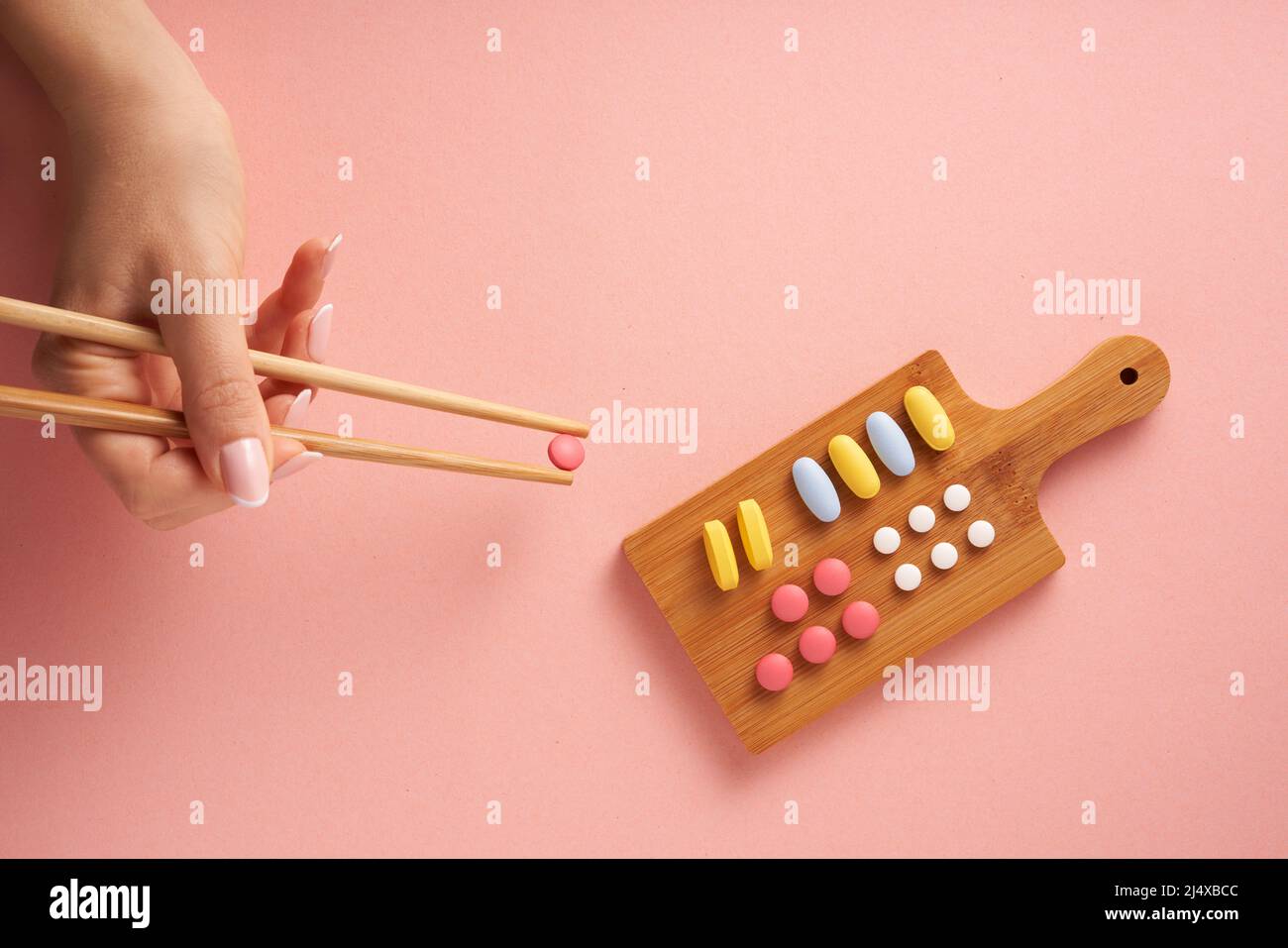 Concepto creativo plano de la foto con la variedad de vitaminas del suplemento nutritivo y de las píldoras dispuestas como plato del sushi sobre fondo rosado. Diseño mínimo. Foto de stock