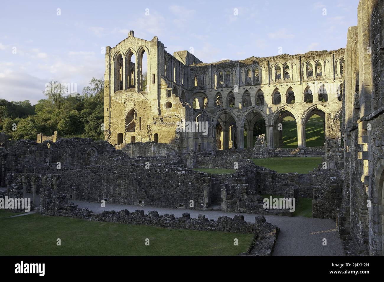 Vista del Presbiterio y del crucero sur a través del claustro de la enfermería y la casa Abbots de la abadía cisterciense de Rievaulx en ruinas Foto de stock