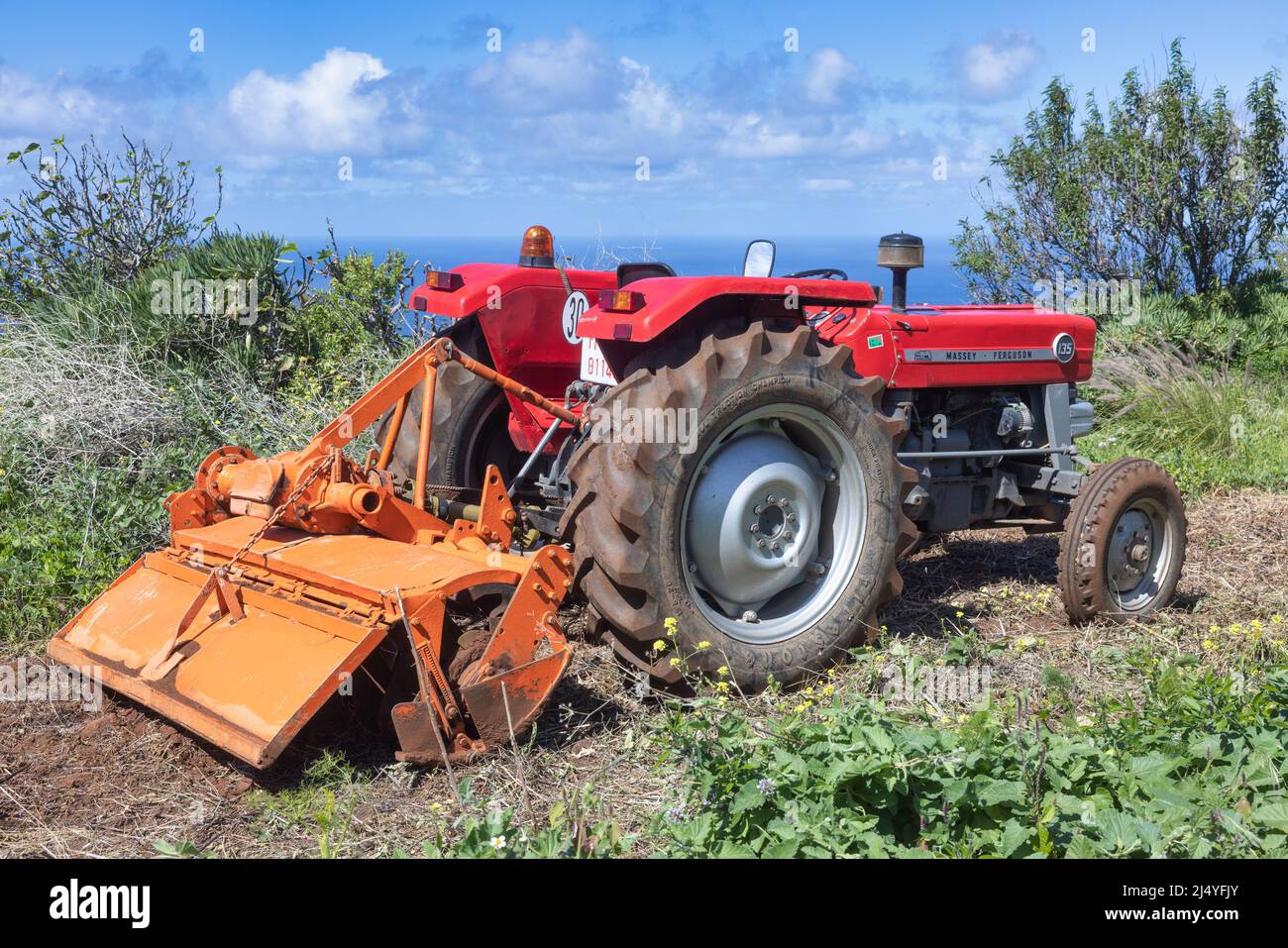 Isla La Palma España - 06 de marzo de 2022: Tractor rojo en campos verdes con vista al mar en la isla de la Palma Foto de stock