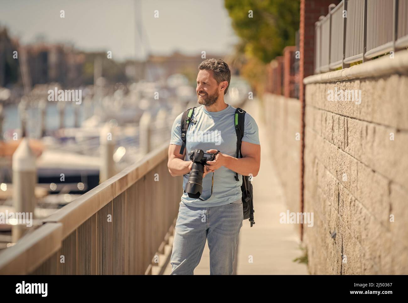 El hombre sostiene la cámara de pie en el paseo marítimo. Fotografía de vacaciones. Fotografía de viajes Foto de stock