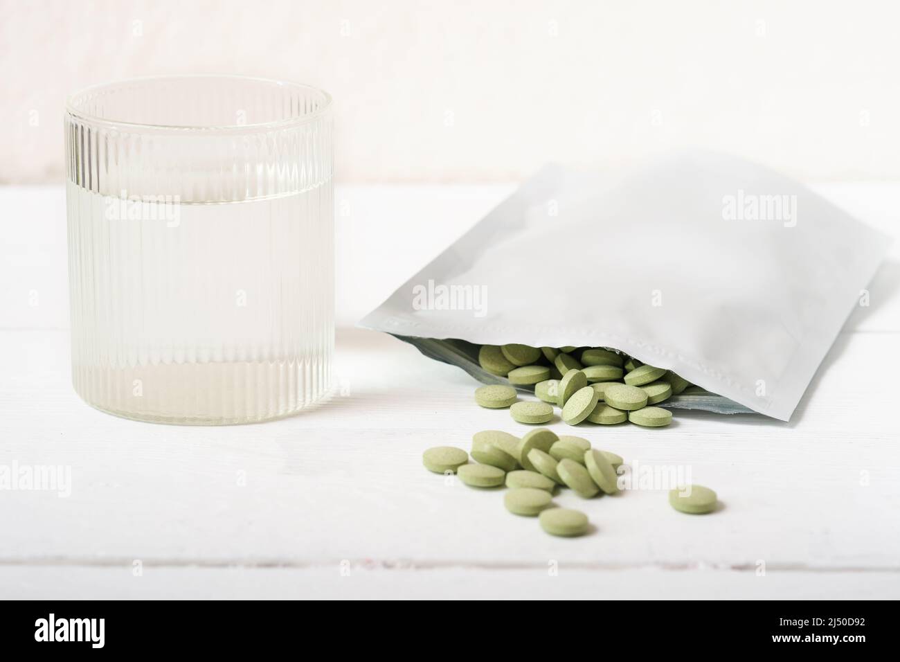 pastillas de pasto de cebada en una mesa junto al vaso de agua. Tabletas de  Spirulina y clorella para el suplemento de desintoxicación y metabolismo.  Superalimento vegano crudo Fotografía de stock -